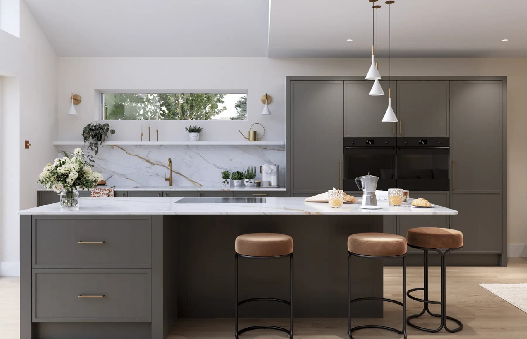 Graphite-grey cabinetry with slim brass bar handles, a marble worktop and splashback, and a full-height bank of ovens