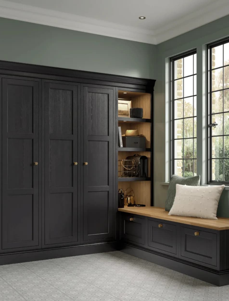 Near-black in-frame storage with three tall doors, an oak-lined open bay lit from above and an oak-topped window bench with drawers under it