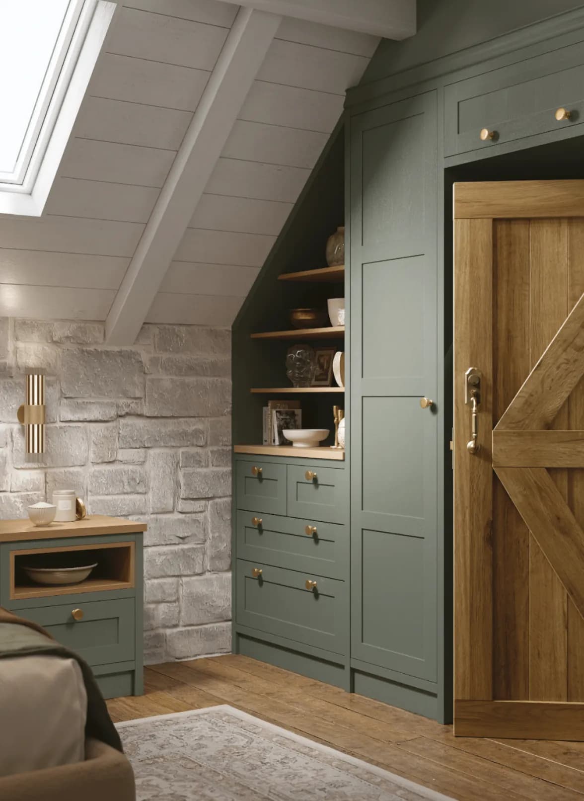 Fitted sage-green joinery under an attic slope — tall cupboards, a drawer bank and oak open shelves — on a wide oak plank floor beside an oak ledge-and-brace door