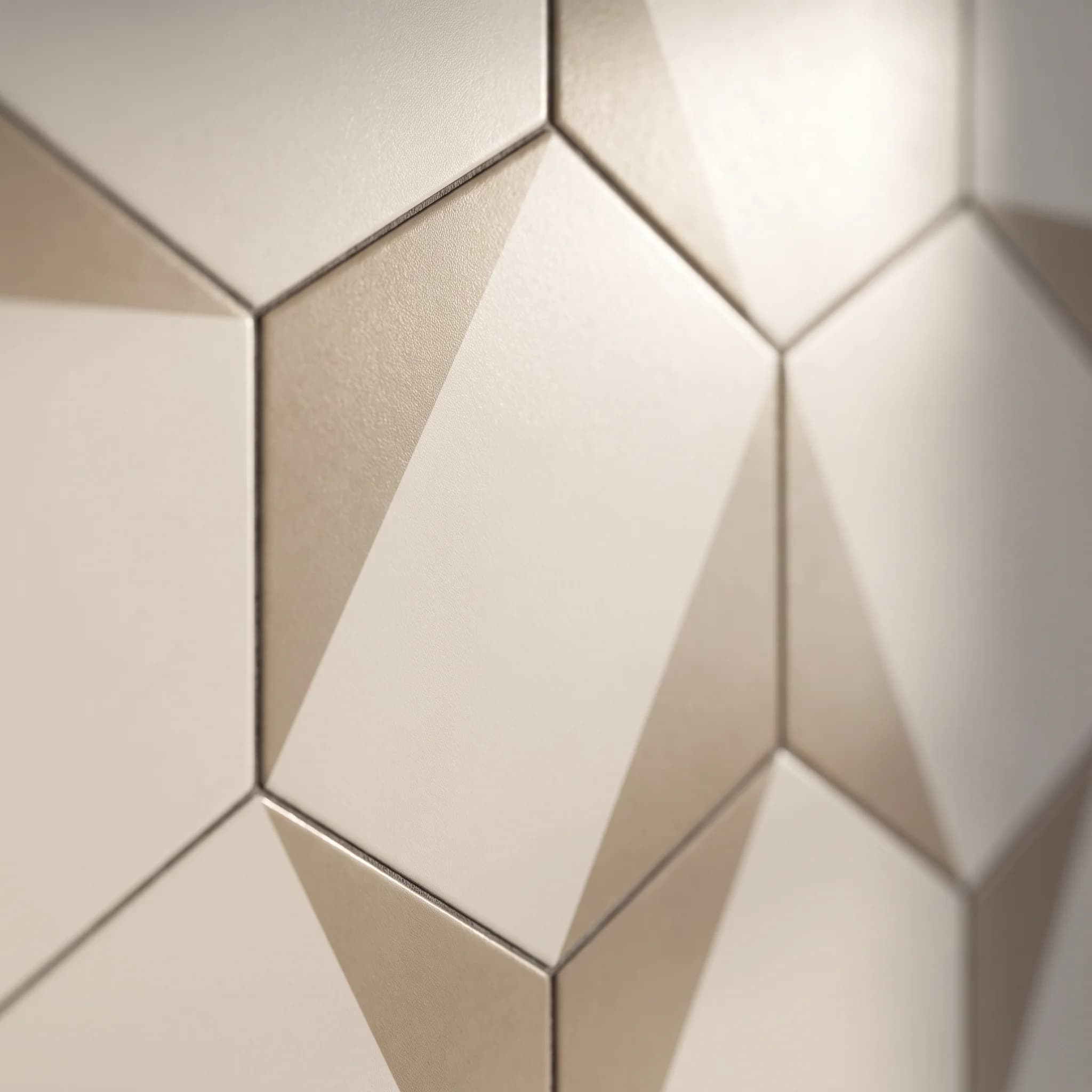 A wall of bevelled hexagon tiles in a cream glaze, raking light across the facets